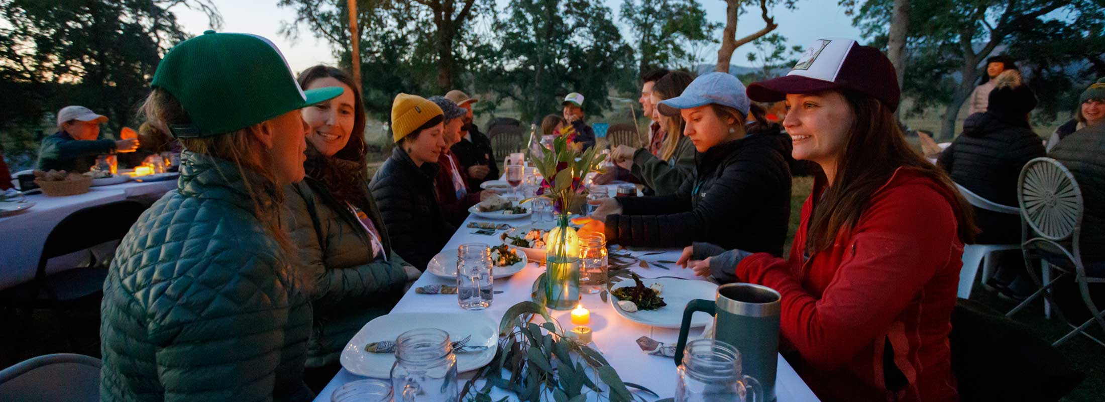 A group of friends gather around an outdoor table for a holiday dinner party